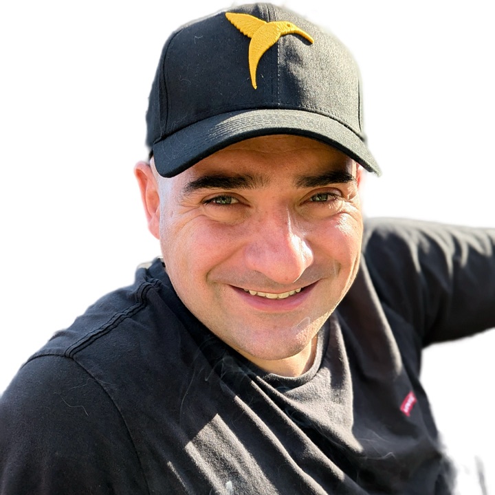 Giuseppe Arici, smiling, in a cap with a yellow bird on it.